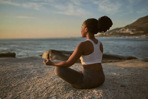 black woman meditating at the beach